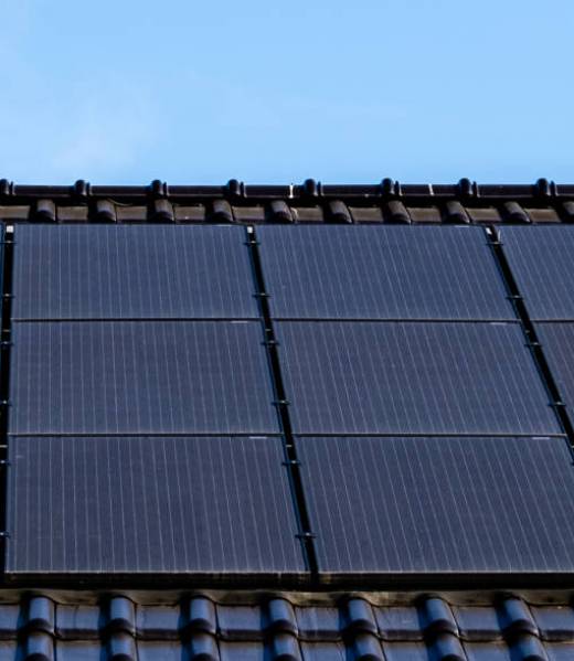 Newly build houses with black solar panels on the roof against a sunny sky Close up of new building with black solar panels. Zonnepanelen, Zonne energie, Translation: Solar panel, , Sun Energy