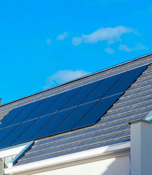 Newly build houses with solar panels attached on the roof against a sunny sky Close up of new building with black solar panels. Zonnepanelen, Zonne energie, Translation: Solar panel, , Sun Energy.