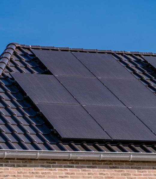 Newly build houses with solar panels attached on the roof against a sunny sky Black solar panels attached on the roof against a sunny sky Close up of new building with black solar panels. Zonnepanelen, Zonne energie, Translation: Solar panel, , Sun Energy