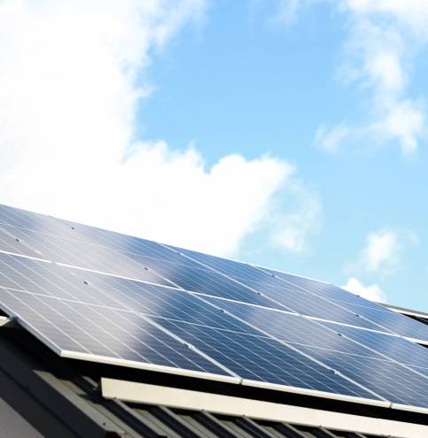 Solar panel cells on cloudy blue sky background. Clean alternative energy power concept. Modern house with solar panels stand-alone photovoltaic plant system on metal sheet roof. Go green